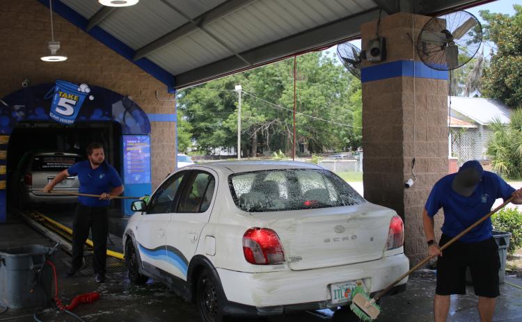 Ronald Morris (from left) and Dillon Geiger, Take 5 Car Wash general manager, prep a car with a washing session on Wednesday morning. (TONY BRITT/Lake City Reporter)