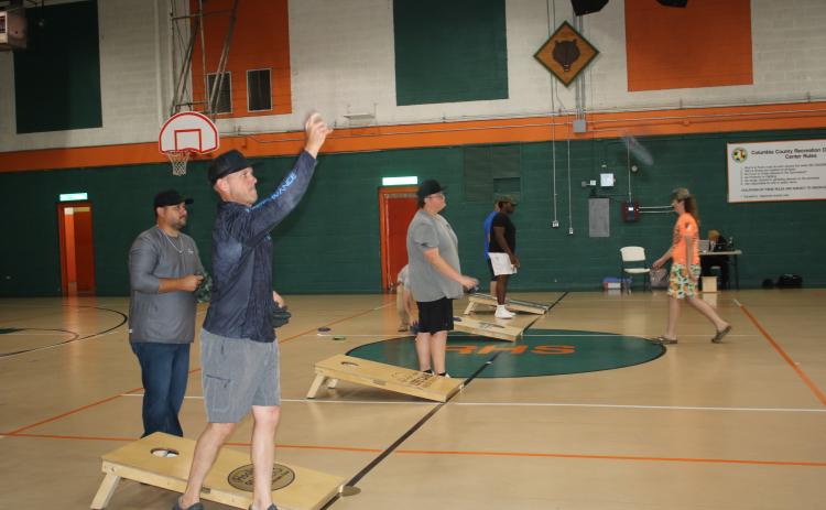 Stephen Jones (far left) follows through after tossing a bag in a cornhole match at the Richardson Community Center on Thursday night. (TONY BRITT/Lake City Reporter)