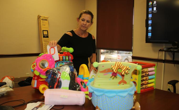 United Way of Suwannee Valley Executive Director Jennifer Anchors looks over some of the items that the organization will sell at its community yard sale Friday. (TONY BRITT/Lake City Reporter)