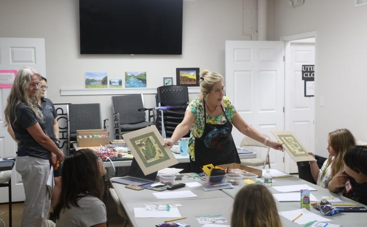 Laura Hunter-Null with the Gateway Art Gallery shows collages to students in an art literacy class Wednesday. The Gallery has partnered with Altrusa of Lake City on the program to teach literacy skills to children. (MORGAN MCMULLEN/Lake City Reporter)
