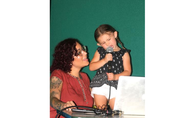 Amberlyn Gould (left) helps her three-year-old daughter, Addison, during a karaoke performance Wednesday night at Gators Dockside. (TONY BRITT/Lake City Reporter)