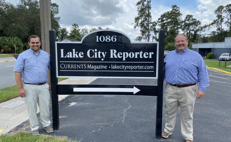 Lake City Reporter Editor Jamie Wachter (left) and Publisher Todd Wilson stand beside the newspaper’s relocated sign street side at 1086 SW Main Blvd., where the newspaper has relocated to Suite 103 of the former Social Security office complex. The Reporter completed its move earlier this month after selling its 11,000 square foot building on Duval Street downtown to Columbia County earlier this year. The signs were moved earlier this week. (JULIA GASPARRINI/Lake City Reporter)