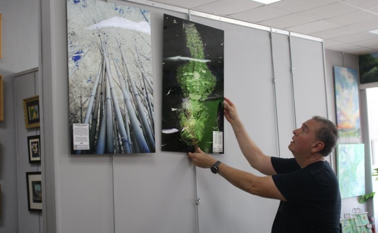 Hugo Cruz hangs some of his infrared photographs up at the Gateway Art Gallery. Cruz is the Gallery’s featured artist for August. (TONY BRITT/Lake City Reporter)