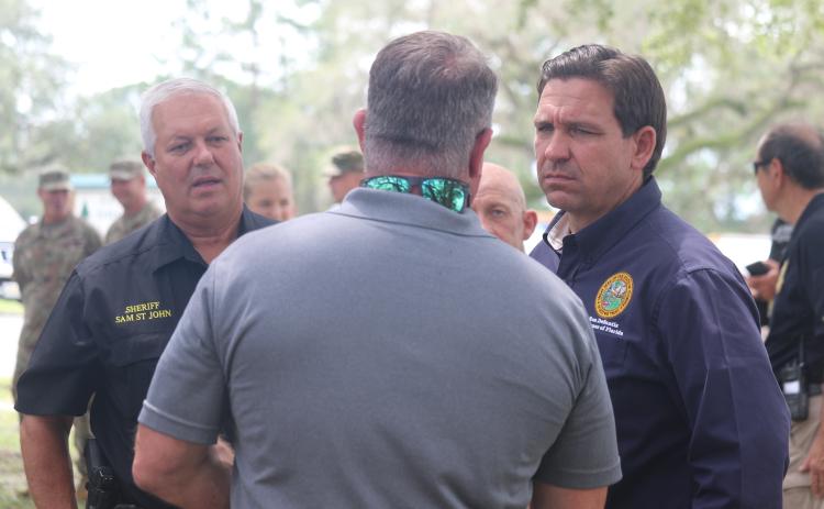 Gov. Ron DeSantis (right) talks with Suwannee County Commission Chairman Franklin White and Sheriff Sam St. John Friday afternoon in Live Oak. (JAMIE WACHTER/Lake City Reporter)