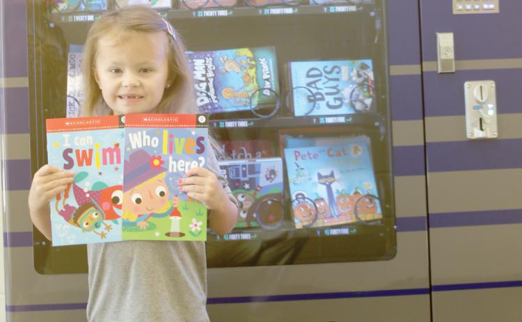 Belmont Academy kindergarten student Rylie Halks shows off her two books out of the book vending machine at the school. (JAMIE WACHTER/Lake City Reporter)