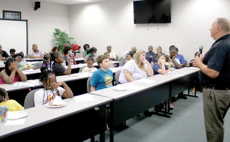 Lake City Police Chief Gerald Butler speaks to a group of more than 35 children on Friday afternoon about the importance of staying in school. (TONY BRITT/Lake City Reporter)