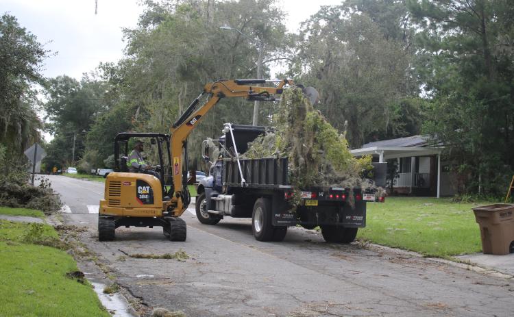 A public works employee with the City of Lake City, loads storm debris into a dump truck on Friday. (TONY BRITT/Lake City Reporter)