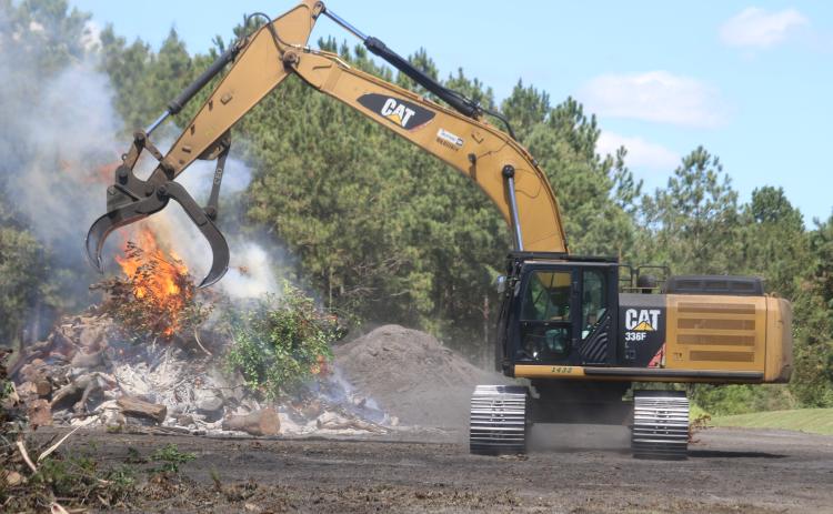 An operator dumps additional debris onto a fire at the Columbia County Public Works department in Lake City. The county also has a site in Fort White open to clear debris following Hurricane Idalia. (TONY BRITT/Lake City Reporter)