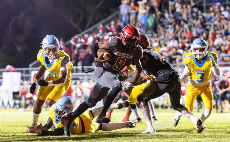 Lafayette quarterback Tywan Williamson leaves a pair of Chiefland defenders behind him on a touchdown run Friday night at Dale Walker Field. (JACK HOWDESHELL/Special to the Reporter)