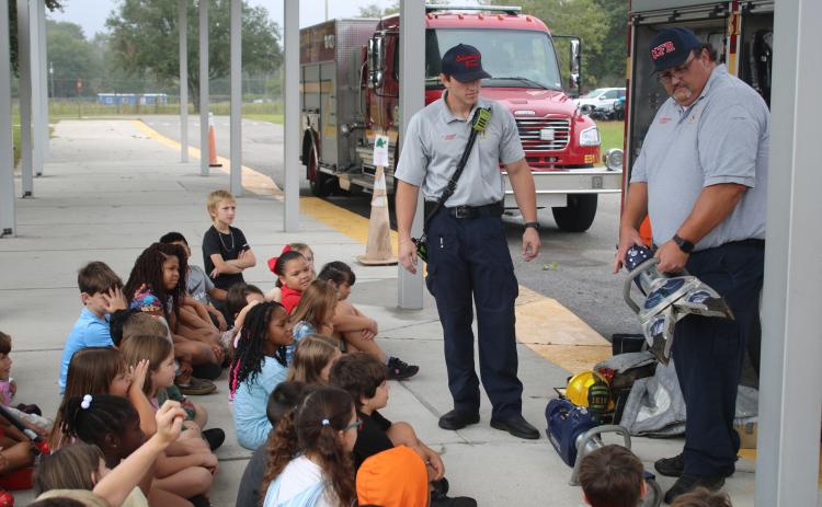 Tyler Vickery (left) and Cody Bertram, Columbia County Fire Rescue firefighters, demonstrate the Hurst Jaws of Life for Westside Elementary School second grade students for Fire Prevention Month. (TONY BRITT/Lake City Reporter)