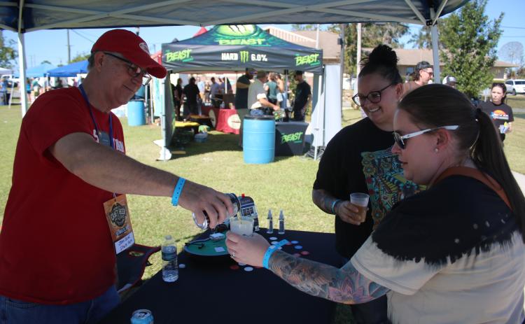 John Kasak (clockwise from left) pours cider for Gateway City Craft Beer and Wine Festival visitors Whitney Martin and Ashley James. (TONY BRITT/Lake City Reporter)