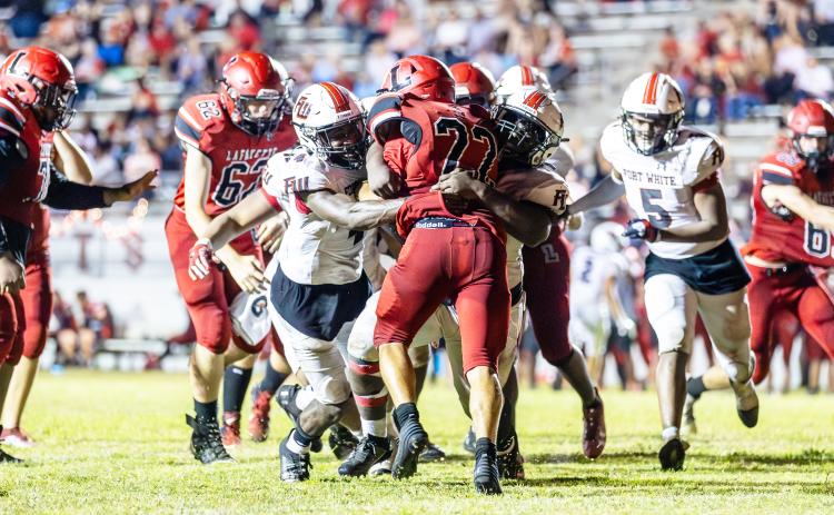 Maliki Clark (4) and the Fort White defense tackle Lafayette running back Tavis Hutson last Friday. (JACK HOWDESHELL/Special to the Reporter)