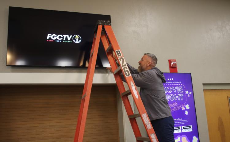 Florida Gateway College Marketing Director Rob Chapman adjusts a television screen in the Levy Performing Arts Center, which is being renovated. (TONY BRITT/Lake City Reporter)