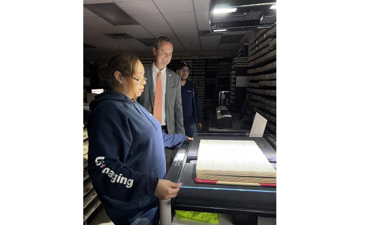 Columbia County Clerk of Court Jay Swisher (center) watches as U.S. Imaging’s Felicia Valdez scans one of the county’s bound historical records in the records vault at the Columbia County Courthouse Thursday. U.S. Imaging’s Brandon Valdez looks on. (JAMIE WACHTER/Lake City Reporter)