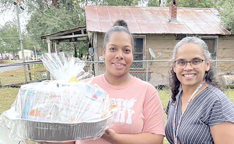 Nilda Soto, a family support specialist with the Early Learning Coalition of Florida’s Gateway, delivers a meal to Maria Alexander, a Season of Giving recipient, earlier this month. (COURTESY)