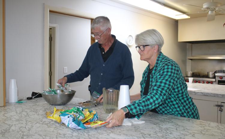 Bob Smith and Jeannie McGalliard, Parkview Baptist Church cold weather shelter volunteers, put out snacks for clients utilizing the facility on Tuesday night. (TONY BRITT/Lake City Reporter)