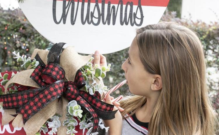Aubree Craig enjoys a candy cane as she looks through decorative door hanger signs at the P.S. We’re Crafty Door Hanger booth at the Holiday Market craft festival in December 2020. (FILE)