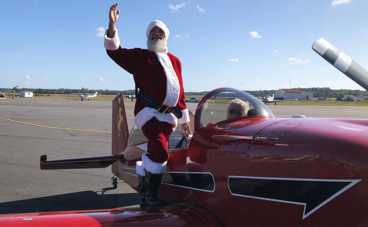 Santa Claus waves after landing in an airplane Saturday at the Lake City Gateway Airport for an event for the local Toys for Tots chapters. (COURTESY)