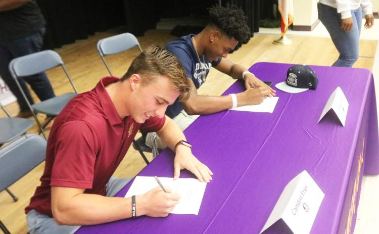 Columbia receiver Camdon Frier (left) signs his letter of intent to attend Florida State while safety Jerome Carter (right) signs his letter of intent with Old Dominion on Wednesday. (JORDAN KROEGER/Lake City Reporter)
