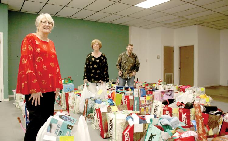 Meally Jenkins (from left), Christmas Dream Machine founder and director, stands amid bags of gifts with volunteers Janet Stanford and Chad Brown on Wednesday afternoon. The Christmas Dream Machine served 616 children this Christmas and was distributing the final bags to families on Wednesday afternoon. (TONY BRITT/Lake City Reporter)