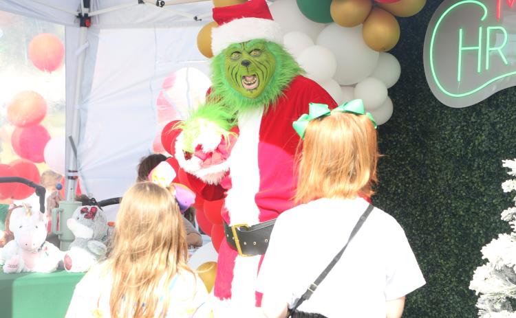 The Grinch reacts to a pair of children approaching him at the City of Lake City’s Holiday Market in downtown Lake City on Saturday. (MORGAN MCMULLEN/Lake City Reporter)