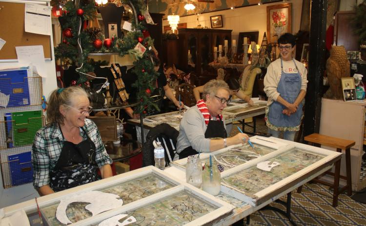 Tina Teasley (from left) and Tami Saperstein paint a snowman on window panes during an art class at the Blue Goose Studio on Thursday afternoon during the Downtown Art Stroll. (TONY BRITT/Lake City Reporter)