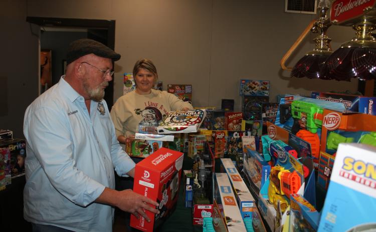 Chris Samson (from left), Exalted Ruler of Lake City Elks Lodge #893, gets help from Brandy Meeks as the two add toys for the Elks Lodge Childrens Christmas Party which will take place Sunday at the building. (TONY BRITT/Lake City Reporter)