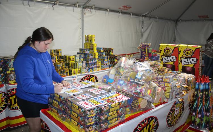 Rorie Lee, a Columbia FFA student, writes a list of prices for the fireworks tent. (TONY BRITT/Lake City Reporter)
