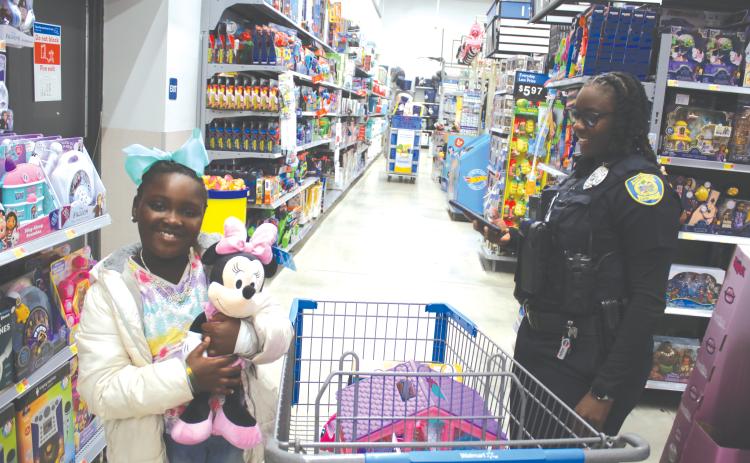 Callie Jones, 7, hugs her Minnie Mouse plush toy while shopping with Lake City Police Officer Aumaria Kelly during Wednesday morning’s Shop With A Cop event. (TONY BRITT/Lake City Reporter)