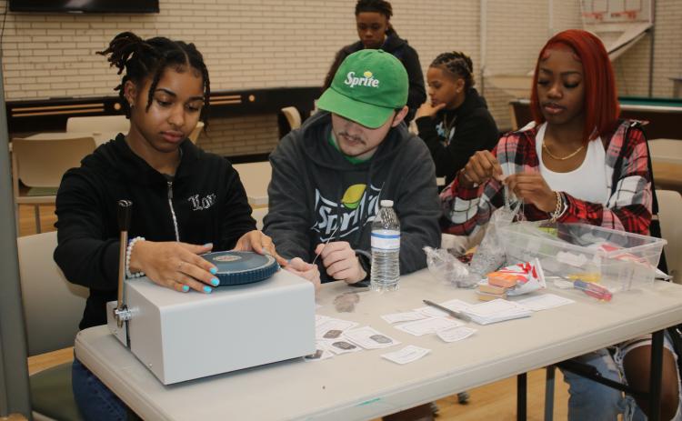 Zamaria Granado (from left) and Hunter Neeley work on making dog tag necklaces for Florida Gateway College students on Wednesday morning. The necklace-making sessions and other activities were part of the school’s welcome back activities for the spring semester. (TONY BRITT/Lake City Reporter)