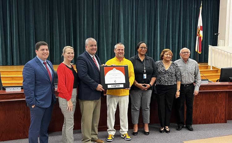 Columbia High Principal Trey Hosford (middle) is presented a framed certificate in honor of the school having 100 years of continuous accreditation. Joining Hosford are School Board members Hunter Peeler (from left) Dana Brady-Giddens, Superintendent Lex Carswell, Assistant Superintendent Hope Jernigan, Narrie Smith and Keith Hudson. (JAMIE WACHTER/Lake City Reporter)