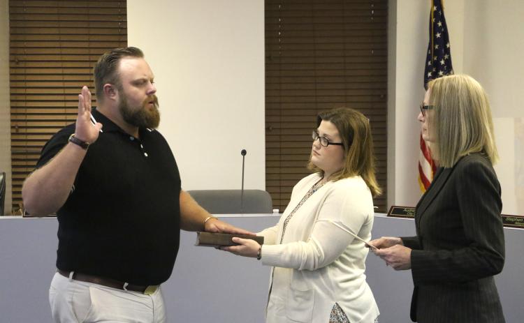 James Carter (left) is sworn in as a member of the Lake City Council by City Clerk Audrey Sikes (right) on Monday night after being appointed to the District 13 seat. Carter’s wife, Jenna, holds the Bible for the ceremony. (MORGAN MCMULLEN/Lake City Reporter)