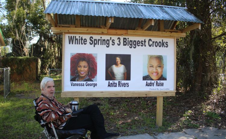 White Springs resident Joe Griffin sits in front of a sign erected on his property that calls Town Manager Vanessa George, Mayor Anita Rivers and Town Clerk Audre’ Ruise ‘crooks.’ (TONY BRITT/Lake City Reporter)