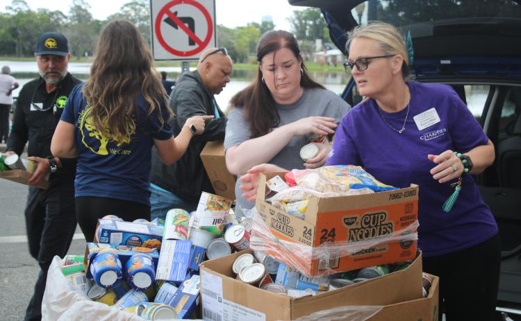 Shannon Moser (from left), Catholic Charities Lake City Regional Director, and Renee LeBlanc fill a box with canned goods and other food items donated by Circle of Life Assisted living facilities. Catholic Charities held its March Against Hunger Walk on Tuesday afternoon at Lake DeSoto. (TONY BRITT/Lake City Reporter)