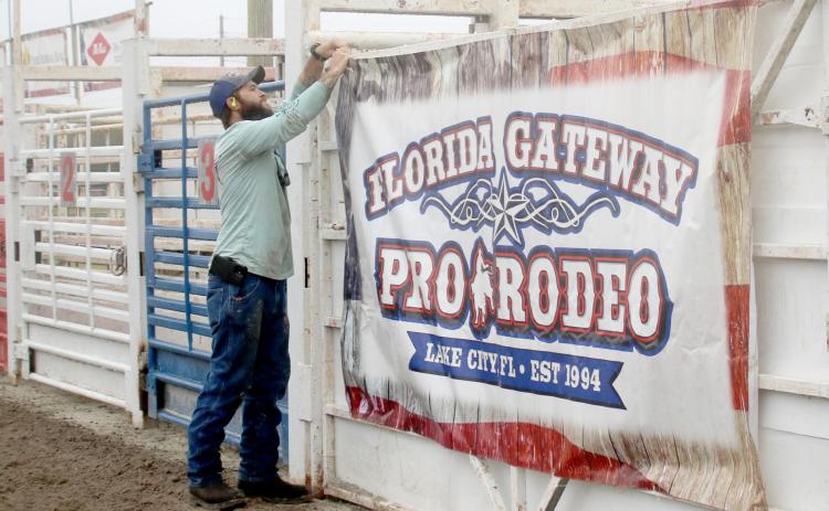 Dyllan Romanik attaches a sign in the Florida Gateway Fairgrounds rodeo arena ahead of the 30th annual Florida Gateway Pro Rodeo, which will take place Friday through Sunday. (TONY BRITT/Lake City Reporter)