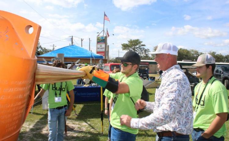 Ethan Humphries (center), a Branford High School student, uses gloves while getting tips from Eric Crawford, a Clay Electric line supervisor, during 2021's Build My Future event. (FILE)