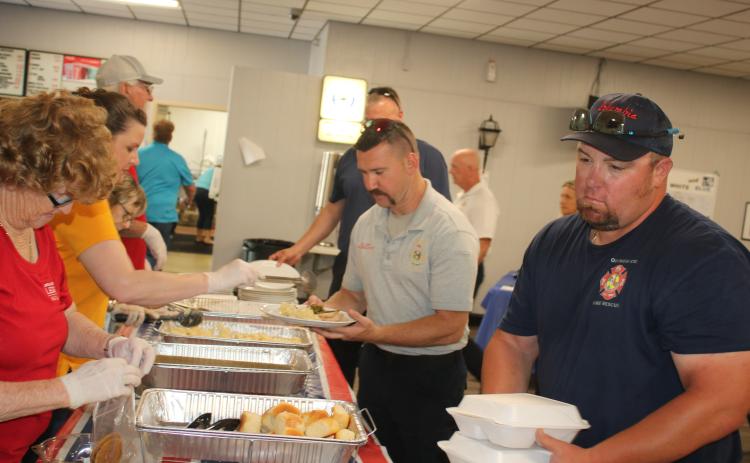American Legion Post 57 volunteers serve meals to Columbia County Fire Rescue personnel Benjamin Fry (center) and Ronnie Crews. (TONY BRITT/Lake City Reporter)