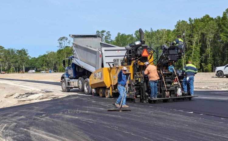 Paving crews from C.A. Boone Construction in Lake City apply smooth asphalt strips to a roadbed in the new Forest Cove subdivision on Wednesday. The new development on Branford Highway just south of Lake City features 14 one-acre lots in a rural setting and is being developed by local contractor Rob Stewart. (COURTESY)