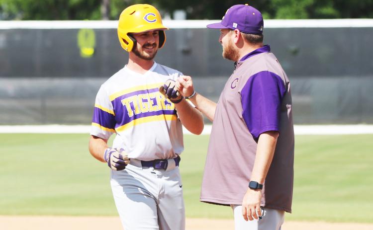 Columbia first baseman Philip Maddox fist bumps assistant coach Joey Edge after hitting an RBI single during Tuesday’s win over The Villages Charter. (JORDAN KROEGER/Lake City Reporter)