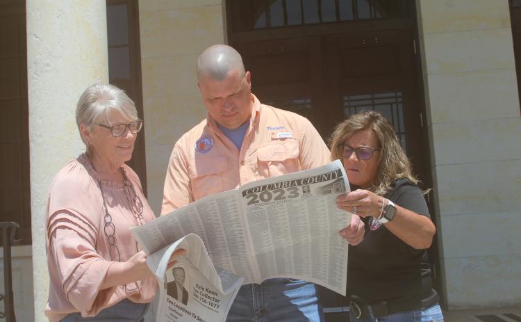 Columbia County Tax Collector’s Office employees La Gina Dow (from left), Thelton Goff and Tracy Nettles look at the county’s delinquent tax rolls Friday as the tax sales certificate auction ended. (JAMIE WACHTER/Lake City Reporter)