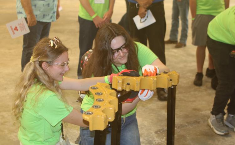 Stephanie Selman (from left) and Natalie Alessi, Fort White High School students, work on adding and removing bolts with an impact driver at the Ring Power vendor’s booth Wednesday morning at Build My Future. (TONY BRITT/Lake City Reporter)