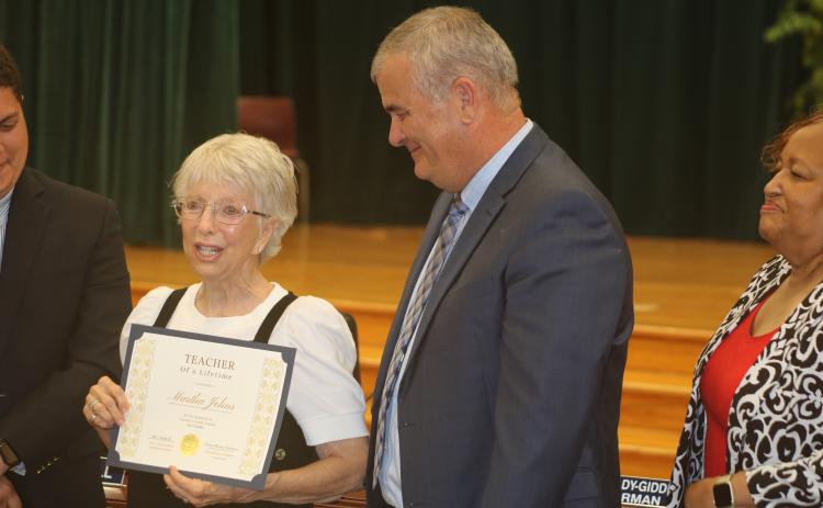 Martha Johns (from left) addresses the audience after getting her Teacher of a Lifetime certificate from Superintendent Lex Carswell on Tuesday evening. (TONY BRITT/Lake City Reporter)