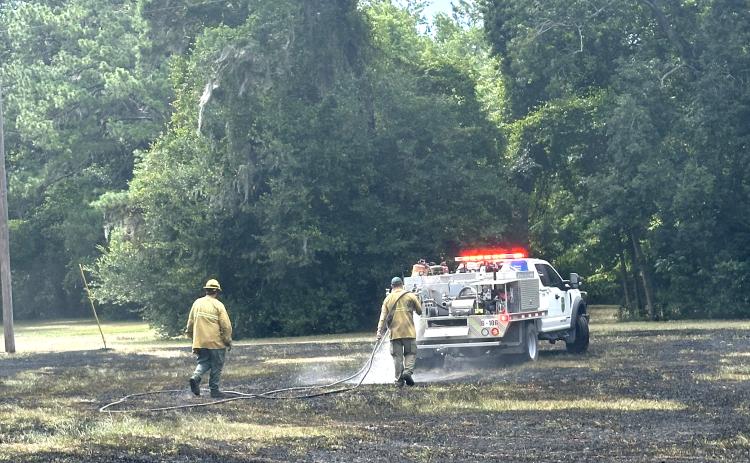 Firefighters with the Florida Forest Service help douse a grass fire at Alligator Lake Park on Wednesday afternoon. The fire was sparked by crossed power lines. (COURTESY)