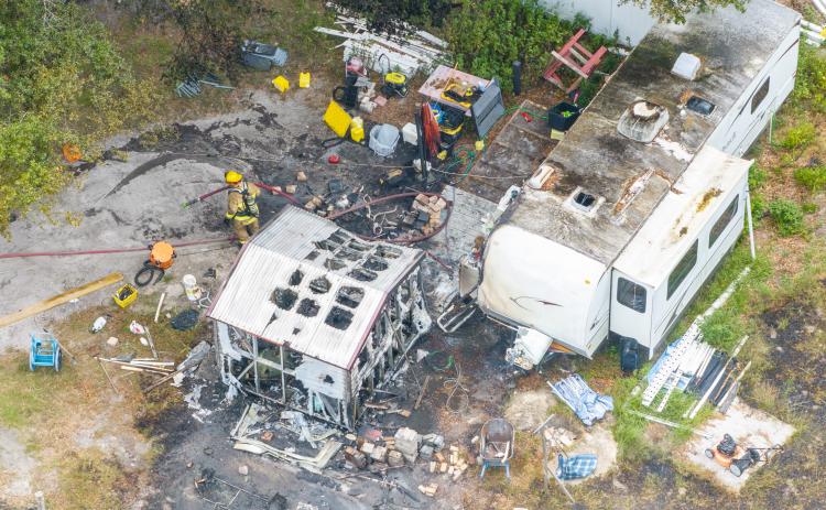 Firefighters sift through debris after a fire consumed an RV camper on State Road 47. (RAY CARPENTER/Special to the Reporter)