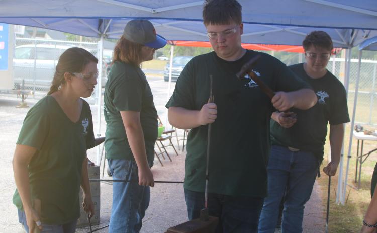 Logan Haley hammers on a metal rod during the Forged in 4-H Blacksmith camp while Erin Harlow, a Columbia County extension agent, looks on. (TONY BRITT/Lake City Reporter)