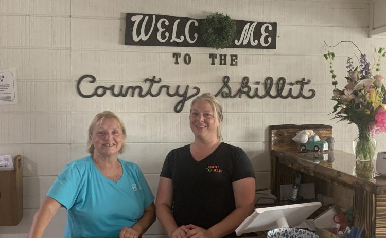 Pam DeLand (left) and assistant manager Stephanie Burgess pose near the entrance to Country Skillit in Lake City. The restaurant just moved to a site across from the Lake City Gateway Airport from Ellisville. (MORGAN MCMULLEN/Lake City Reporter)