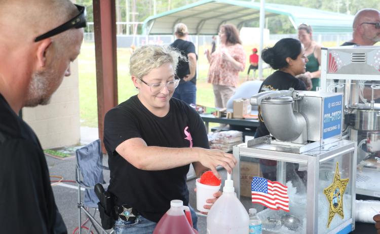 Jessica Chewning, a school resource deputy at Westside Elementary School, prepares a snow cone for a kid during Friday’s Summer Nights activities at Five Points Elementary. (MORGAN MCMULLEN/Lake City Reporter)