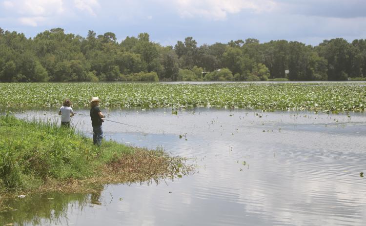 Jamie Spradley (right) and Taylor Kaus, fishing from the banks of Lake Montgomery on Monday, said a new fishing pier would be a nice addition to the lake. (TONY BRITT/Lake City Reporter)
