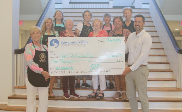 Tina Roberts (front row, from left) stands with other Lake City Garden Club members, as she and Patrick Douglas, of the Suwannee Valley Community Foundation, hold a $10,000 check that was presented to the organization on Wednesday at the Blanche Hotel. Other Garden Club members present include, Ginger McCrannie (second row from left), Cheryl Libert, Kathy Smith and Mary Victores; Jan Logan (back row, from left), Terri Johnson, Sonya Rossin and Dorothy Colvin. (TONY BRITT/Lake City Reporter)