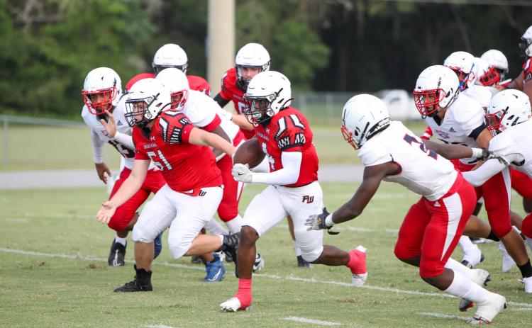 Fort White running back Keimarion Neal bursts through the NFEI defense during Thursday's Preseason Classic. (MORGAN MCMULLEN/Lake City Reporter)